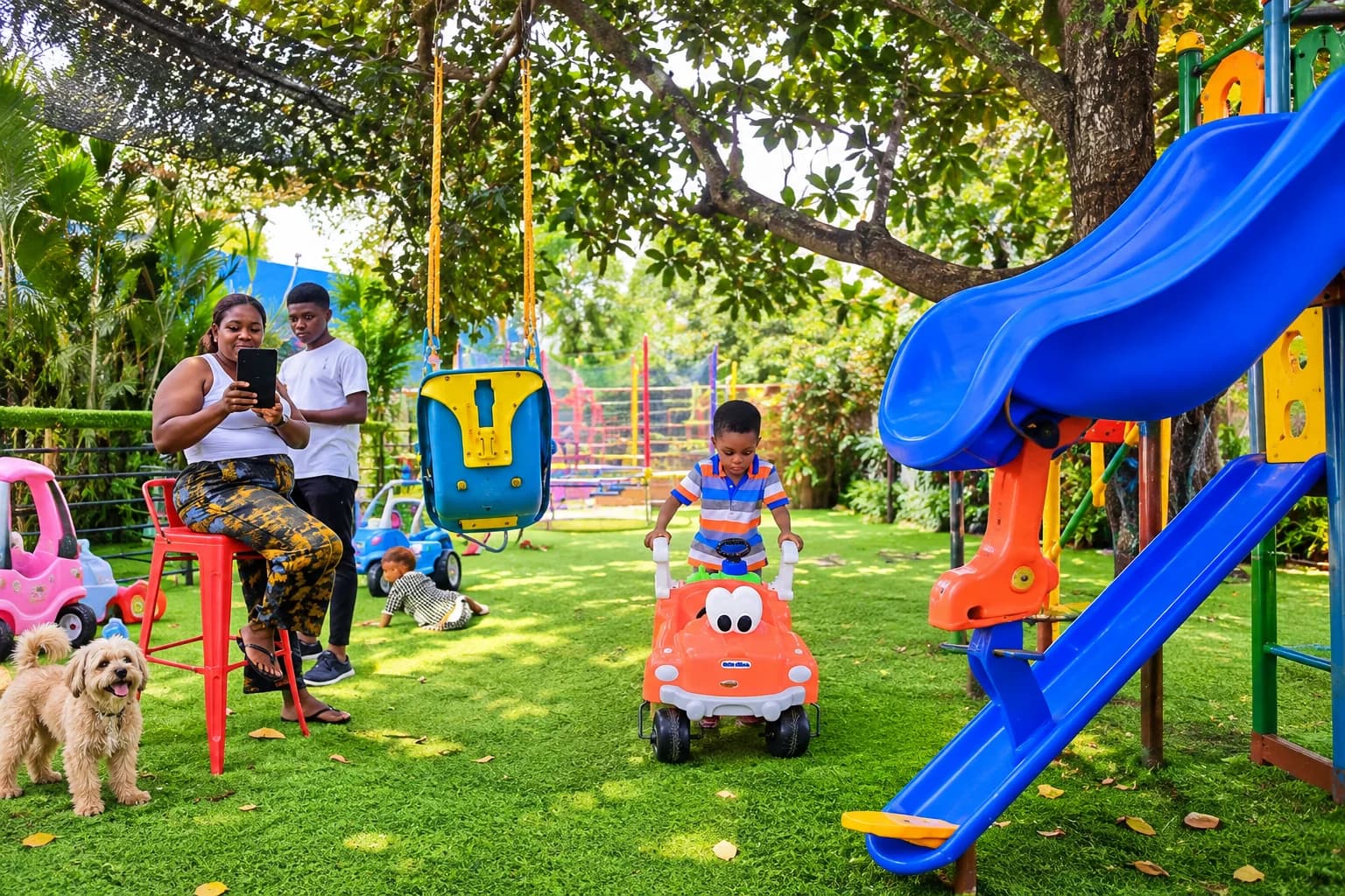 Colourful slide and ride-on toys beneath the playground trees